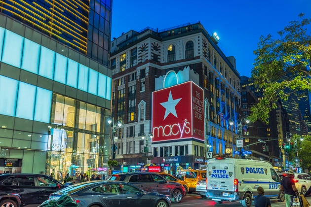 Beautiful view of Macy's store on background of Broadway street with cars, people and police van at night.