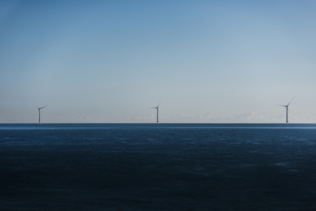 Three offshore wind turbines in Whitley Bay photographed from land on a sunny morning, North Shields, Tyne and Wear, England, United Kingdom