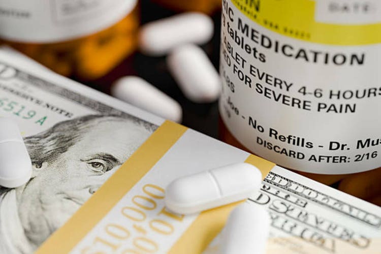 Bottles of medicine and prescription pills sit next to stacks of $100 bills.