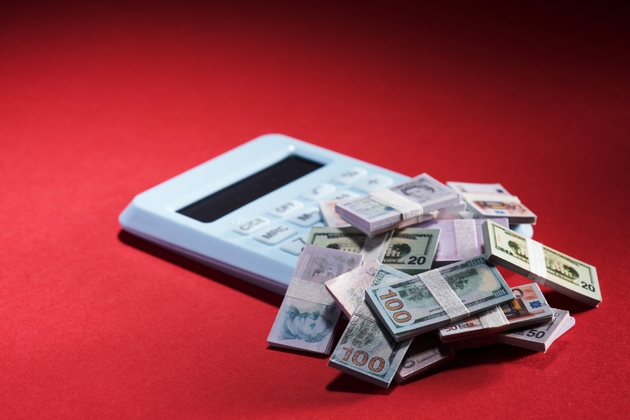 small dollar bill with a calculator in the background portraying declining purchasing power of a deflated dollar and the effects of inflation.