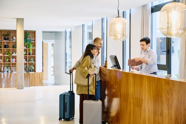 Wide shot concierge showing hotel information to guests at check in