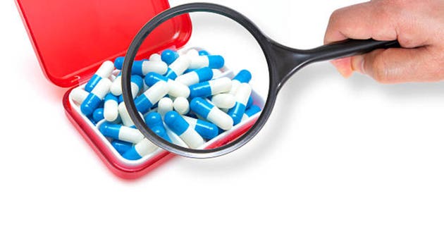 Zooming pills using magnifier glass.