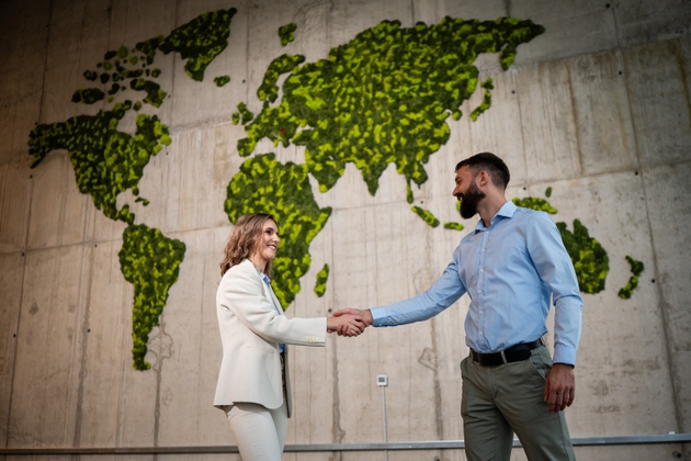 Business partners shaking hands on green world map background