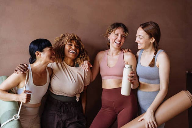 Four Friends In Fitness Gear Laughing Together After A Workout Session