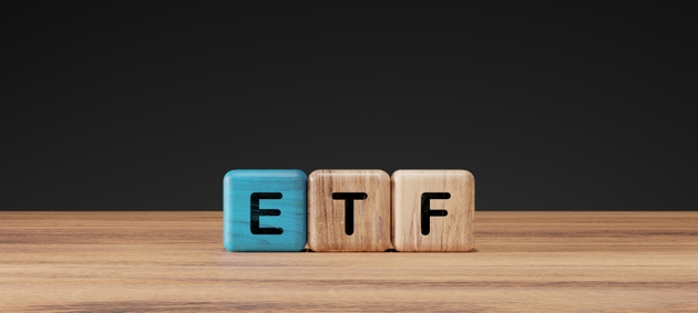 ETF letters on wooden and blue blocks placed on wooden table with dark background. Concept for exchange traded fund, investment, finance, stock market, and economy.