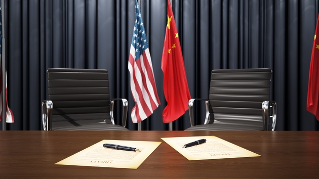 Diplomatic agreement signing between United States and China in formal setting with flags displayed prominently
