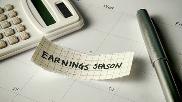 Earnings Season Reminder Note on Calendar with Calculator and Pen for Financial Reporting