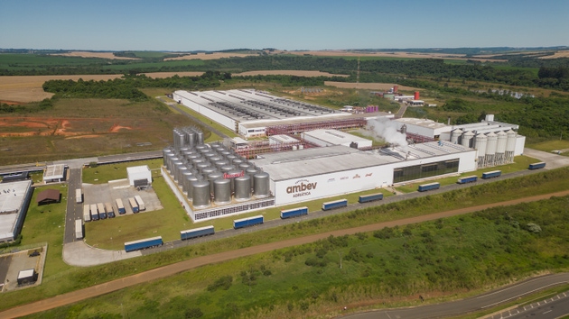 Aerial view of an Ambev factory with trucks and smokestacks