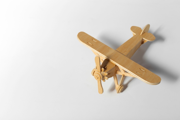 Wooden airplane model crafted from popsicle sticks on a plain white surface