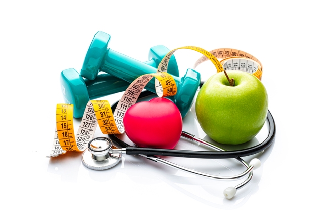 Dumbbells, green apple, stethoscope, tape measure and heart shape. Healthy eating, exercising, weight control for a healthy heart and wellness