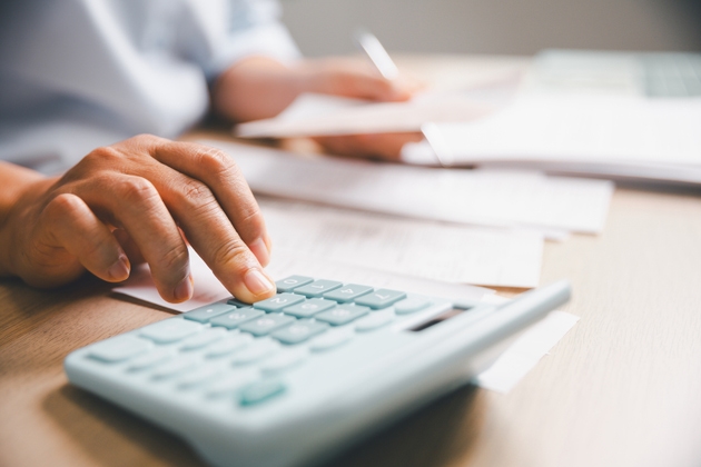 Close-up of office worker calculating financial data with calculator while reviewing receipts, documents, representing accounting tasks, budgeting, expense management, professional financial workflow.