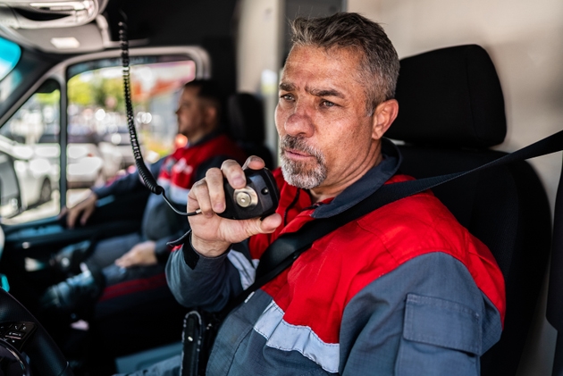 Rescue worker man talking on walkie-talkie at ambulance