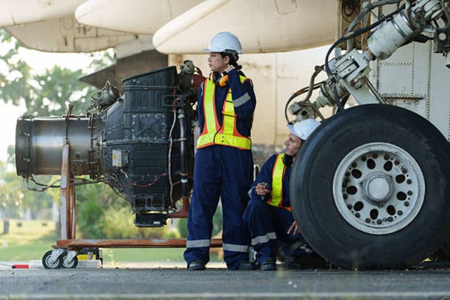 Mechanics inspect the engines of a large plane before takeoff at a summer airport.(PHOTO)