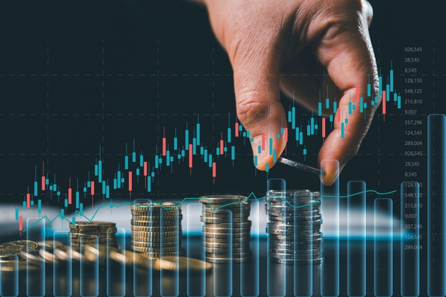 Professional hand stacking coins with an overlay of digital stock market candlestick charts. Concept of financial growth, investment strategy, capital accumulation and wealth management analysis.