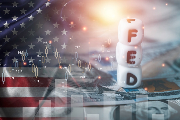 Double exposure of with stacked dice spelling FED on dollar bills , American flag and stock market chart representing interest rate decisions, inflation control and financial markets concept.
