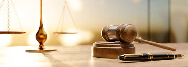 Symbolic representation of justice with scales of justice, gavel, and pen on a wooden desk