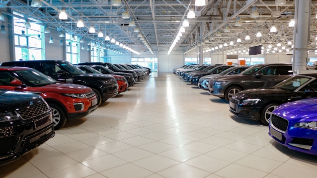 Car dealership showroom interior with rows of new vehicles.