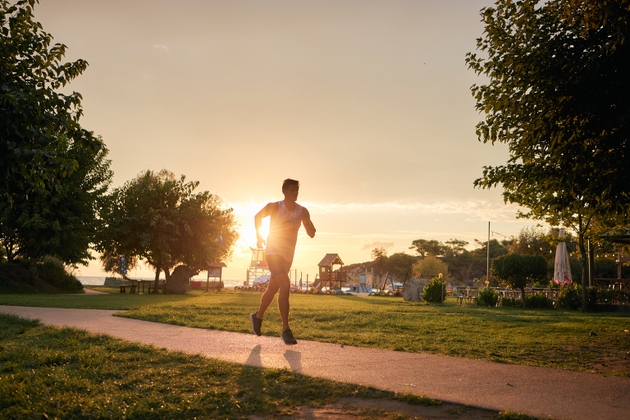 Man running on park path during sunset