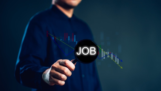 Magnifying glass on JOB with downward chart for economic crisis. This unemployment and job market recession concept shows a professional investigating career loss and financial decline.