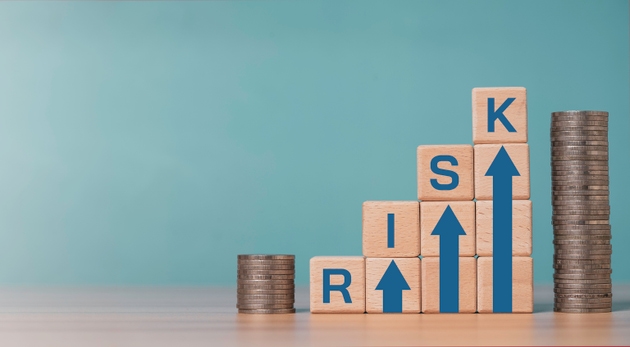 Investment risk and financial concept with wooden blocks forming rising arrows and word risk, next to stacked coins for related of business risk and profit return concept.