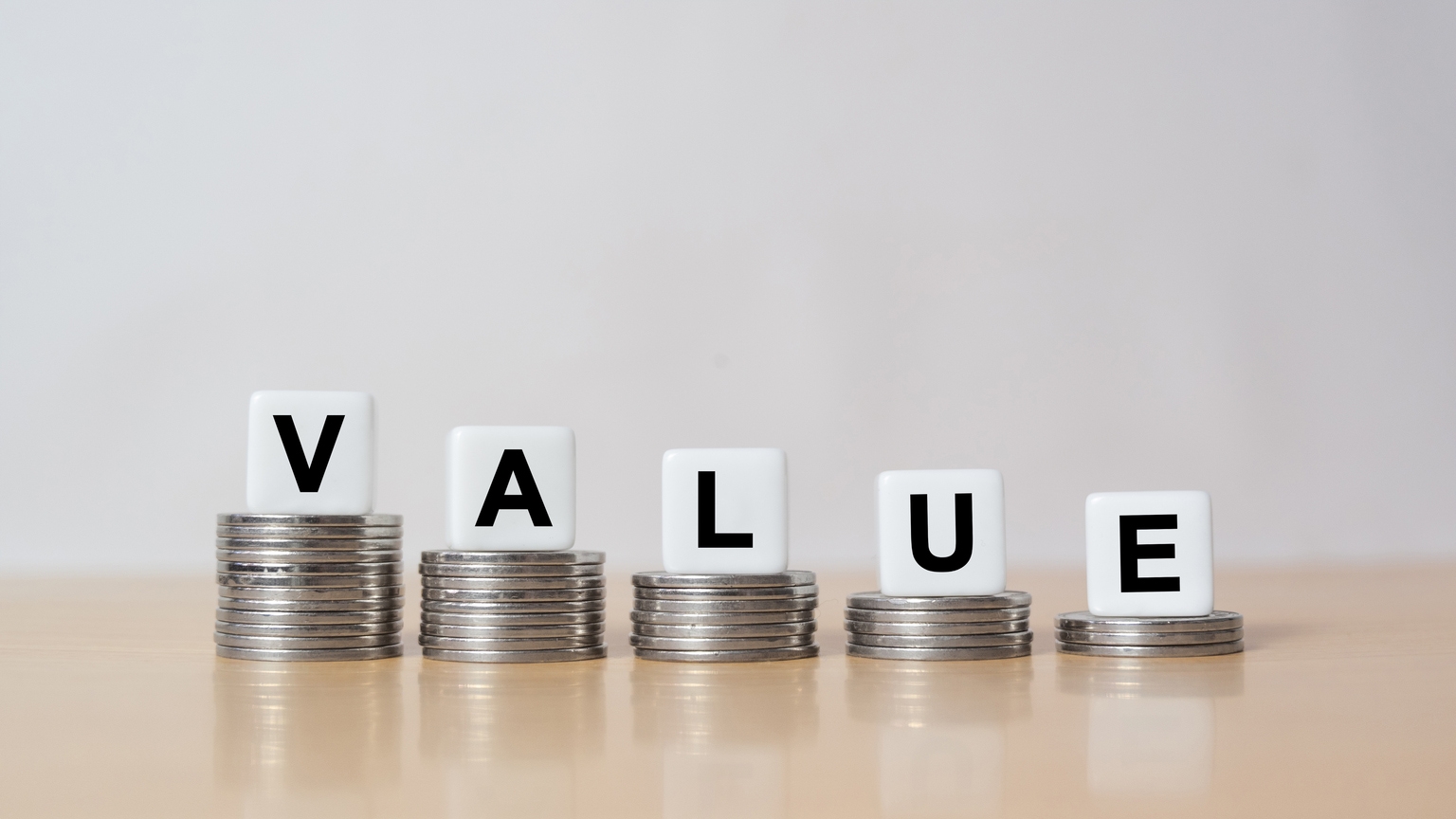 Symbol for decreasing value. Dice placed on stacks of coins form the word value