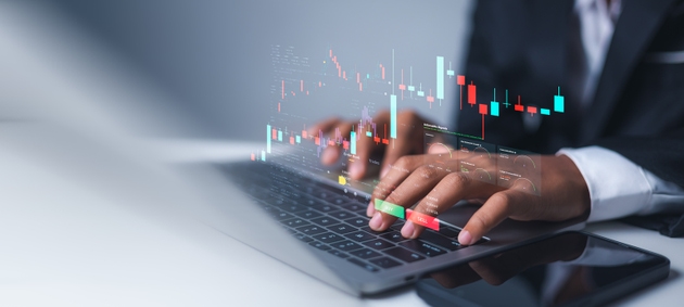 Analyzing financial investment data with virtual candlestick charts and crypto currency graphs on office desk, Businessman hands using laptop for online stock market trading.