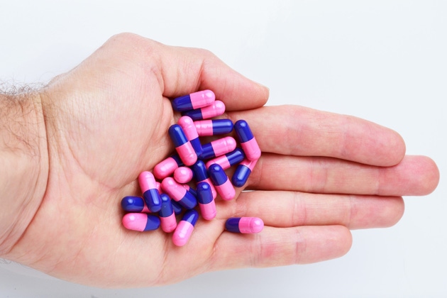 Close-up of human hand holding omeprazole gastro-resistant capsules (proton pump inhibitor) for gastrointestinal treatment