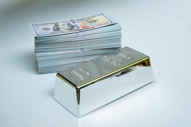 Fine silver bar and pile money banknote 100 USD on a gray background