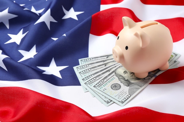 Pink piggy bank with dollars on national American flag, closeup