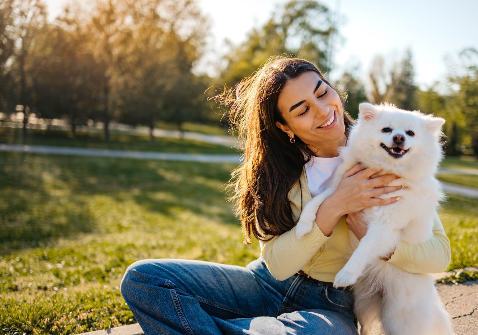 A woman hugs and kisses her dog in the park