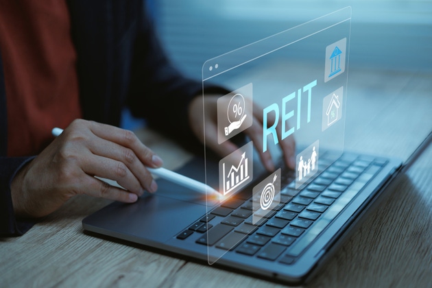 Business professional using laptop and stylus with REIT dashboard, finance icons analytics interface. Concept digital real estate investment, passive income, property funds growth business strategy