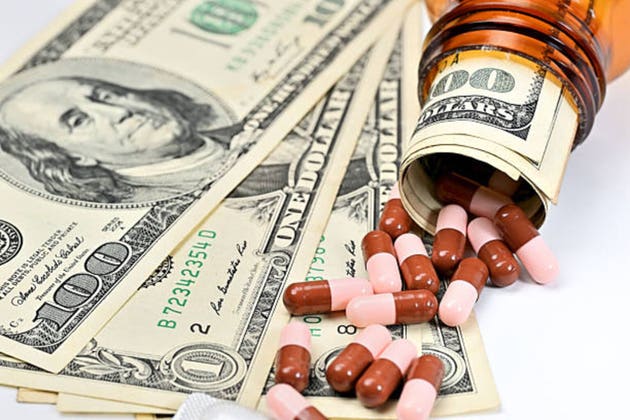 An overturned pill bottle spills cash and medicinal capsules