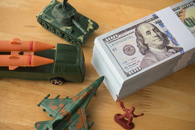 US banknotes, army solider, combat aircraft fighter, tank, missile on wooden table.