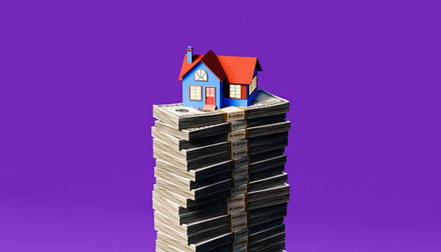 Blue and red roofed house model elevated on towering piles of US currency notes on purple backdrop illustrating property wealth requirement