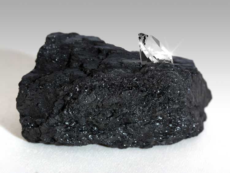 Large sparkling diamond on a black carbon nugget on white