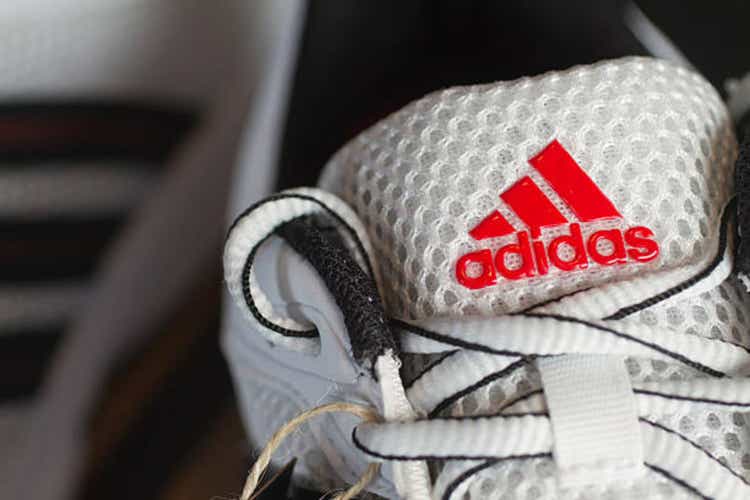 Red Adidas logo on white running shoe