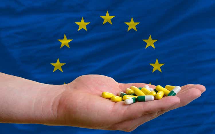 holding pills in hand and flag of europe
