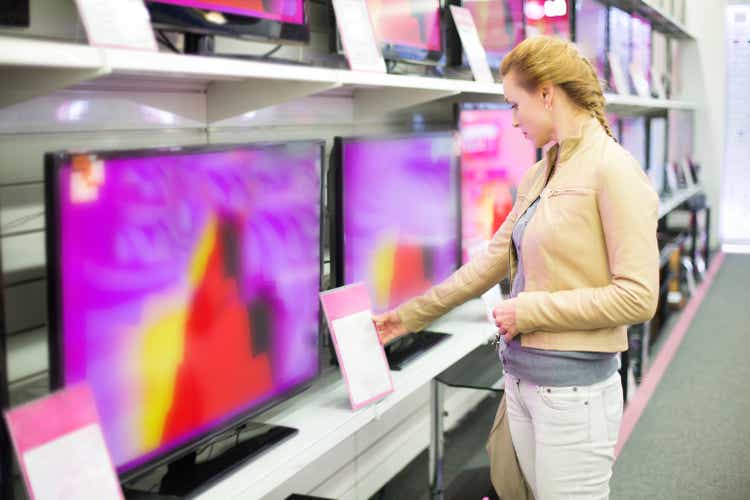 A woman observing prices for a television in a store