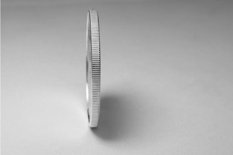 Edge of a silver colored coin balanced on end
