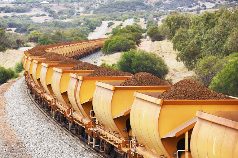 Train loaded with brown hematite iron ore in hills