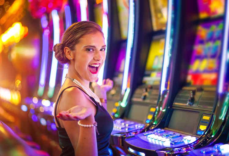 Jeune femme heureuse dans un casino jouant avec des machines à sous