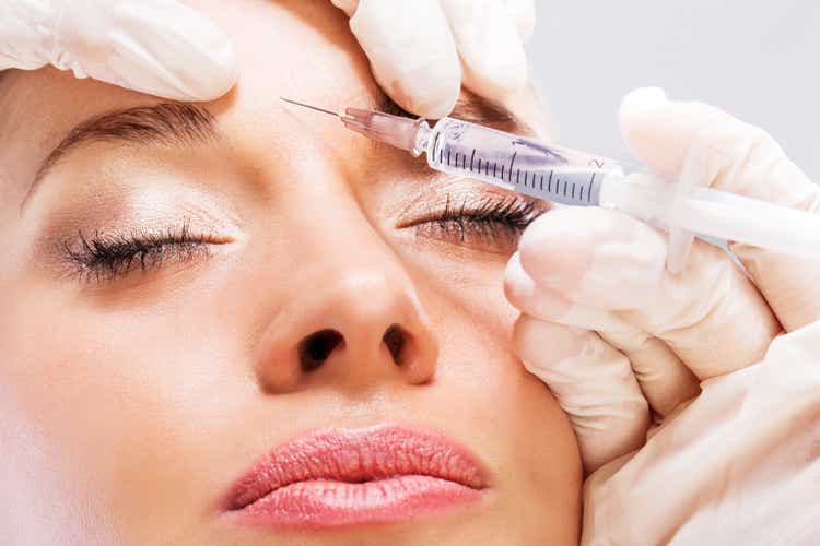 A woman receiving a botox injection in the forehead