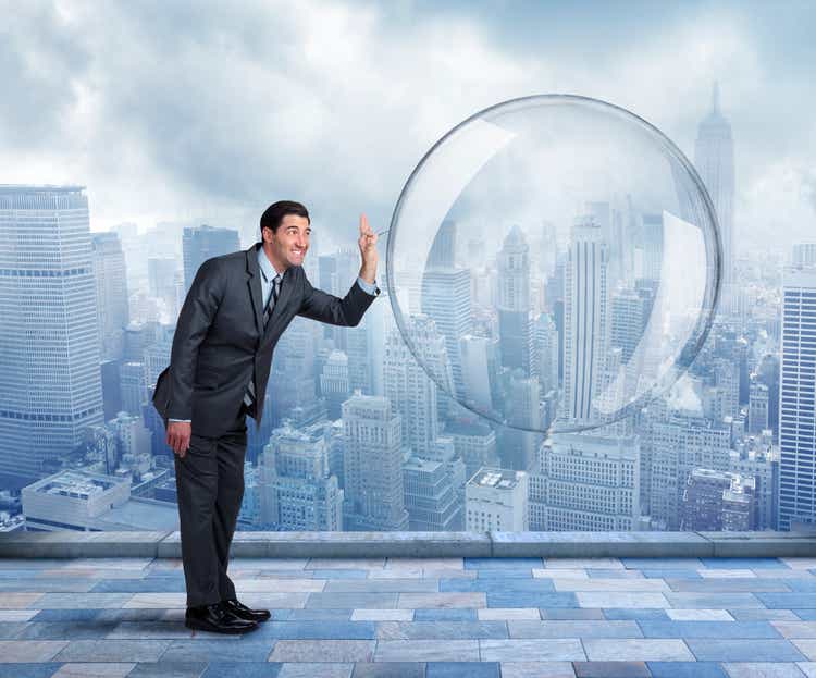 Businessman about to pop a large bubble