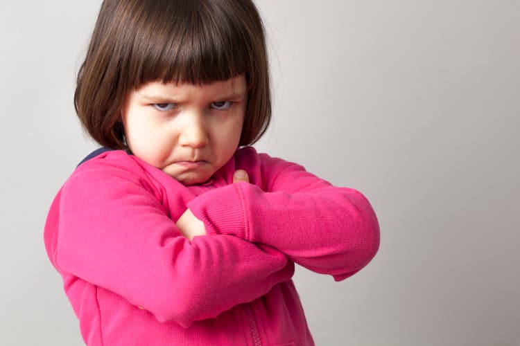 frustrated young child sulking with crossed arms and dirty look