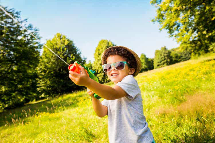 Smiling boy shooting water with squirt gun