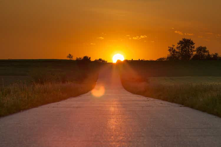 Driving on an asphalt road towards the setting sun