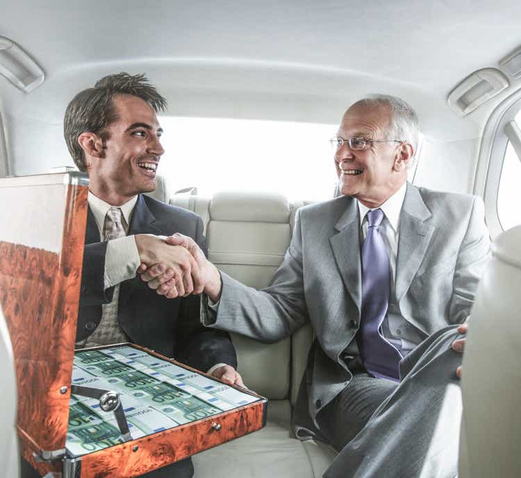 Businessmen shaking hands in backseat of car