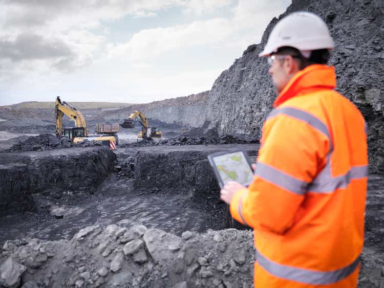 Miner checks plans on digital tablet in surface coal mine