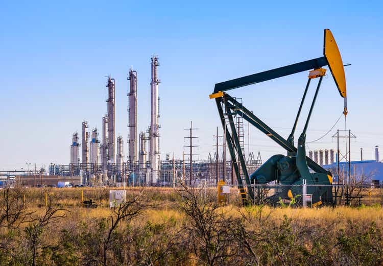 Pumpjack (oil derrick) and refinery plant in West Texas