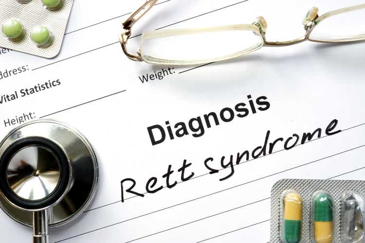 Diagnosis Rett syndrome and tablets on a wooden table.
